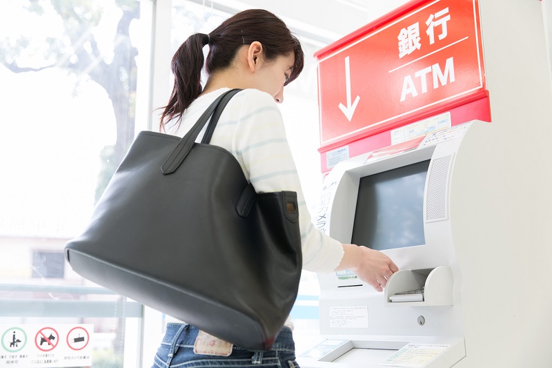 カードローン　返済　端数-ATMで入出金を行う女性