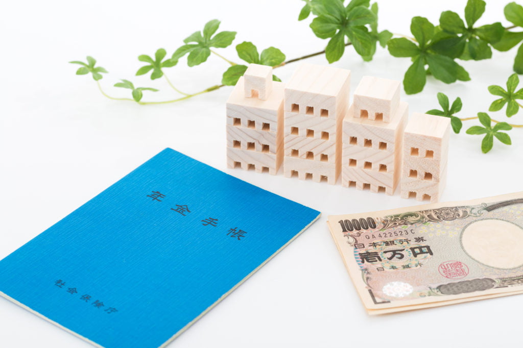 年金担保貸付審査-年金手帳と現金と家の置物